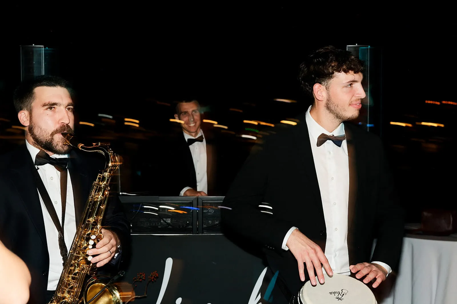 A saxophonist and a percussionist in tuxedos performing at a wedding in Trogir