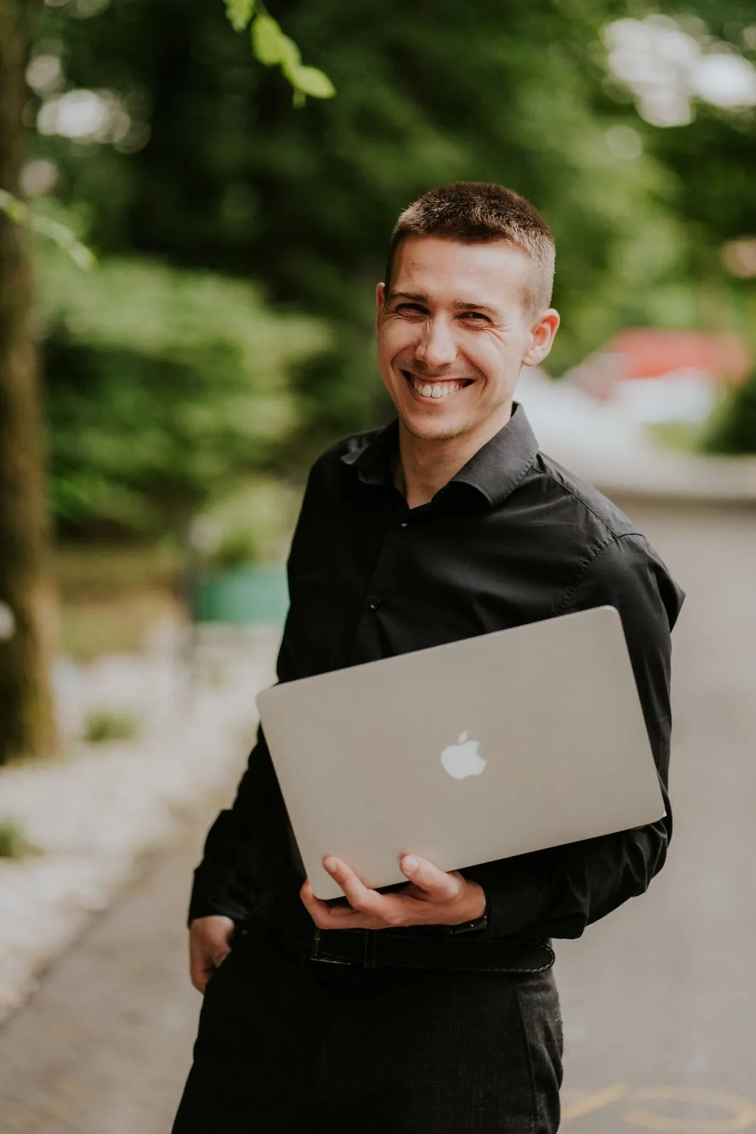 DJ Symart smiling with his laptop in a garden before a wedding