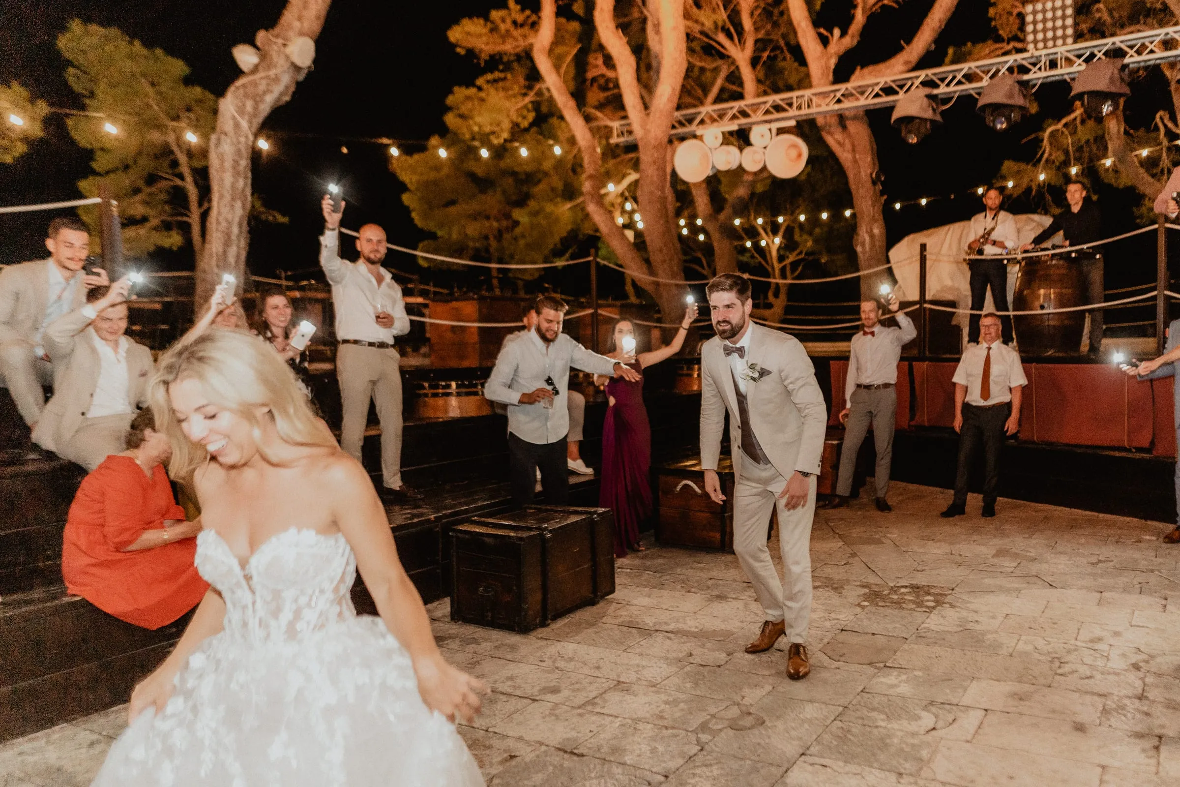 A bride dancing with guests under string lights at Fort George on the island of Vis