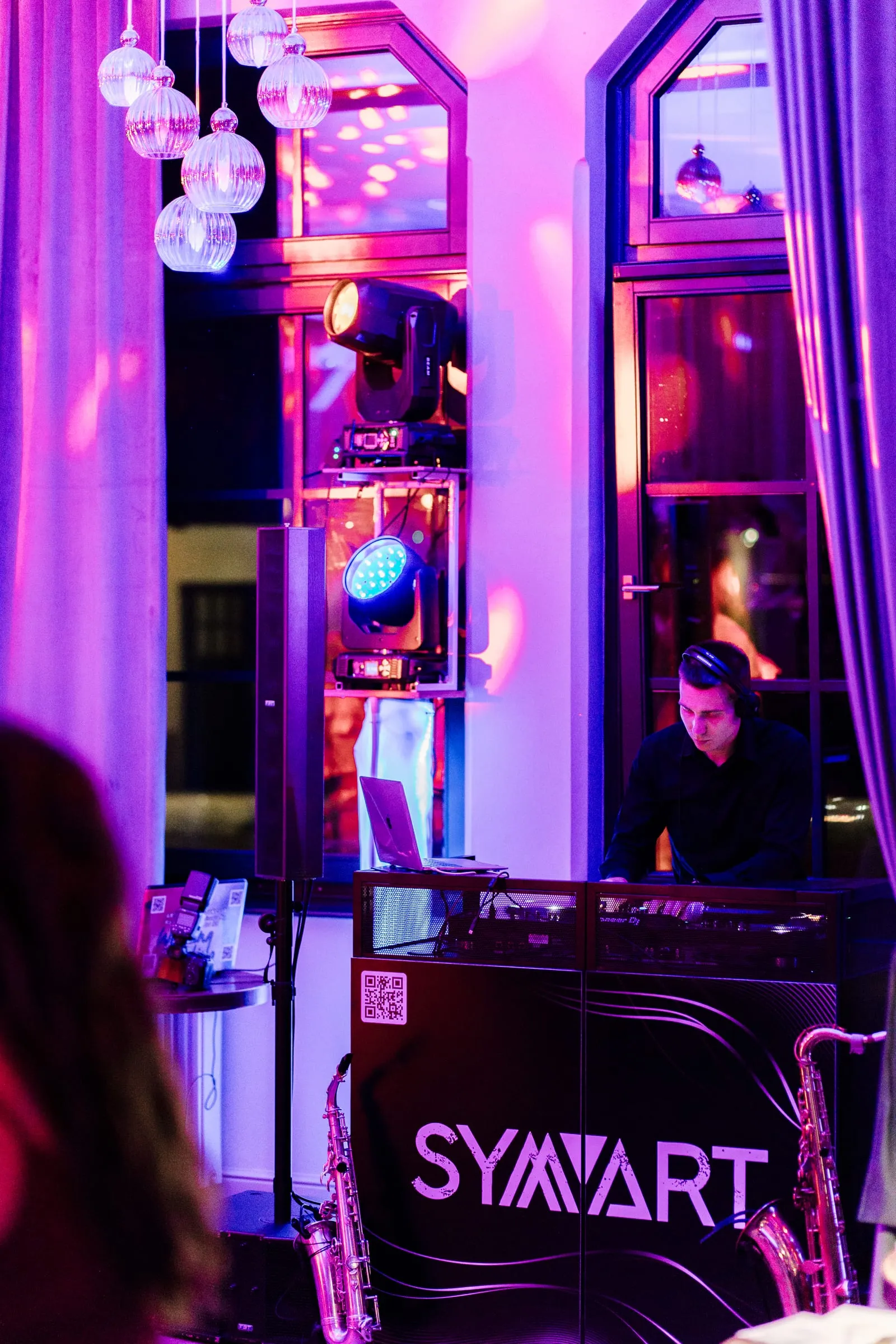 DJ Symart playing behind his lit booth at Restoran Maksimir in Zagreb