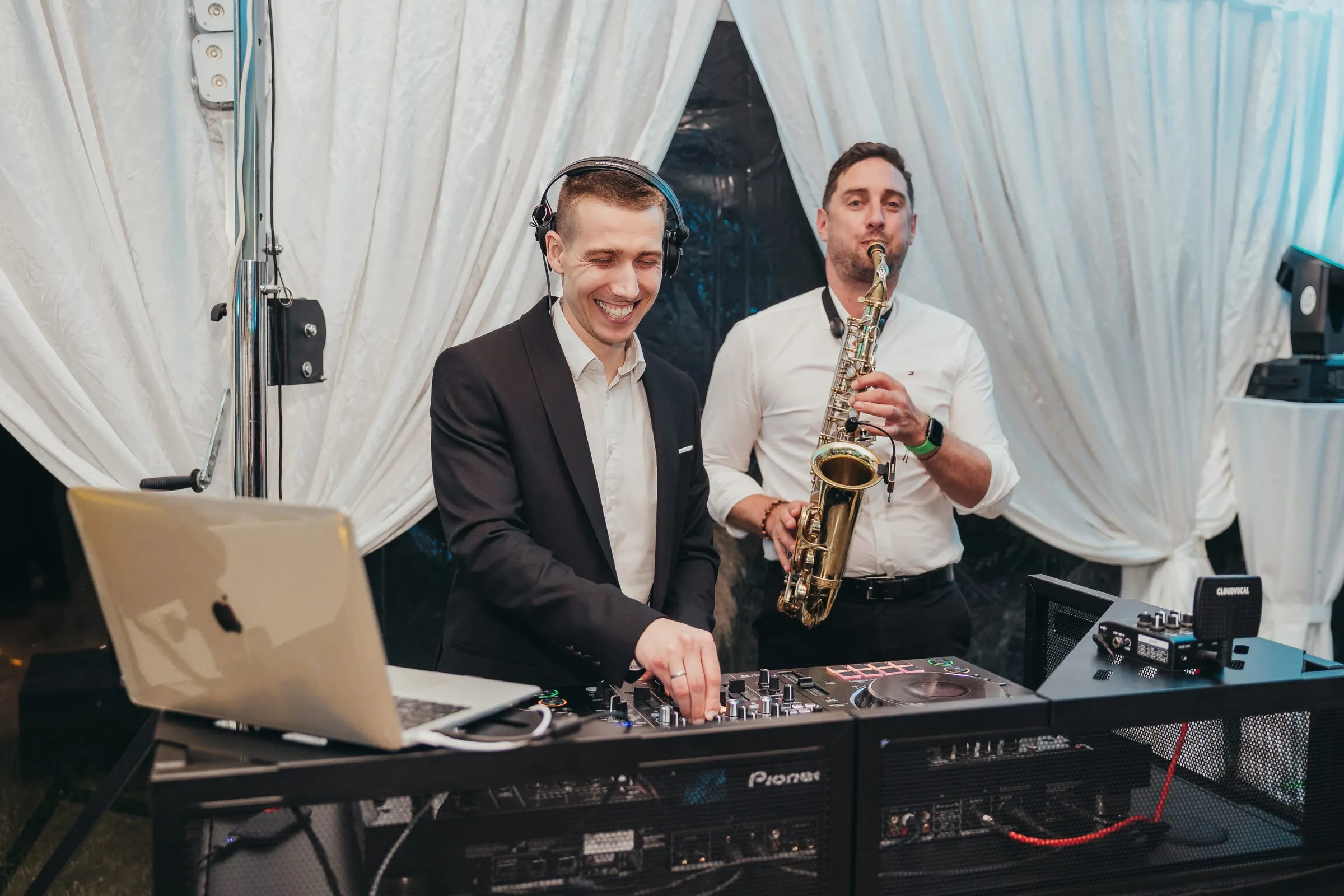 DJ Symart and a saxophonist at the decks under a marquee at Old Village
