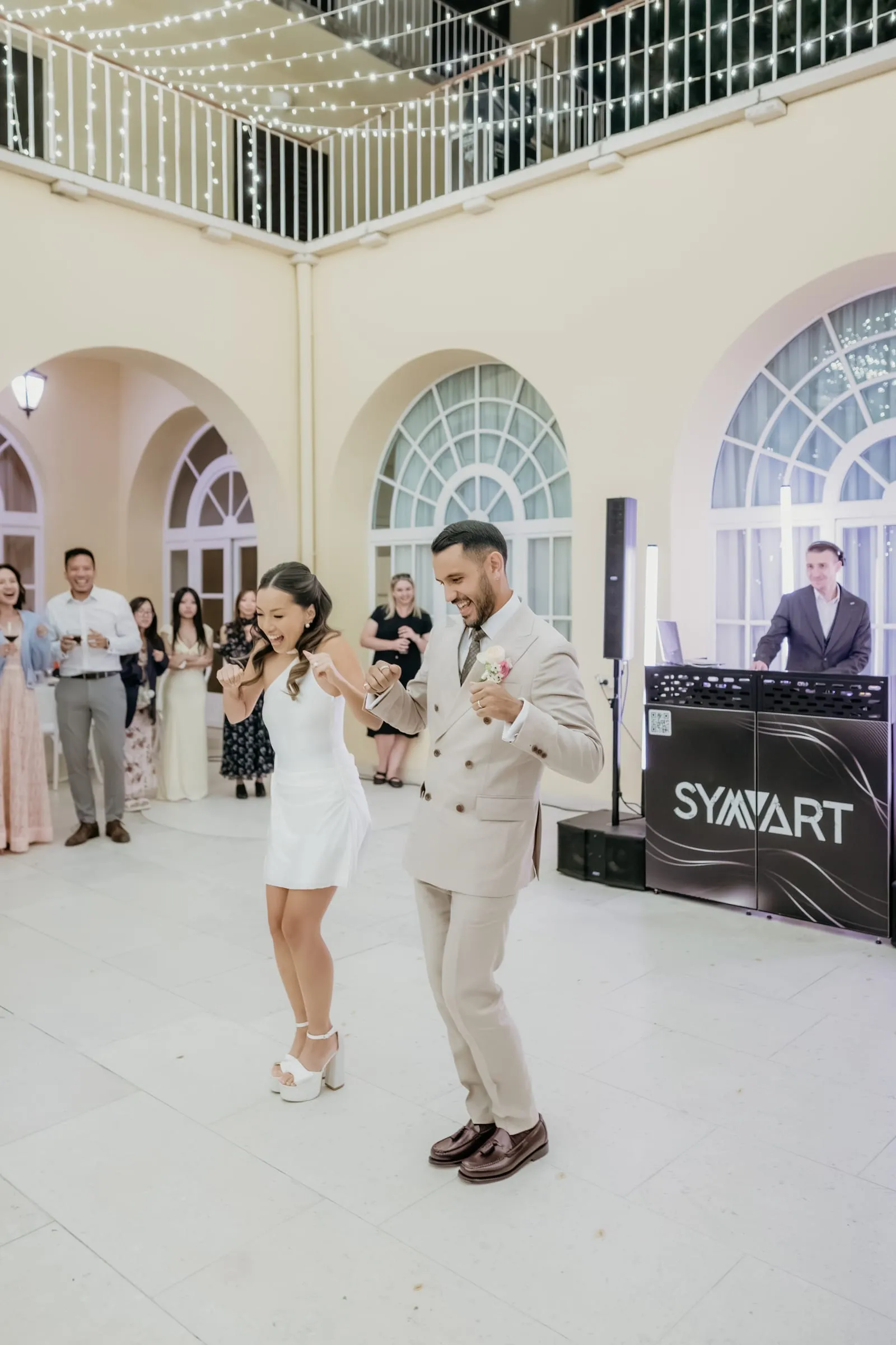 Newlyweds dancing in the arched hall of Villa Dalmacija with the DJ booth behind them