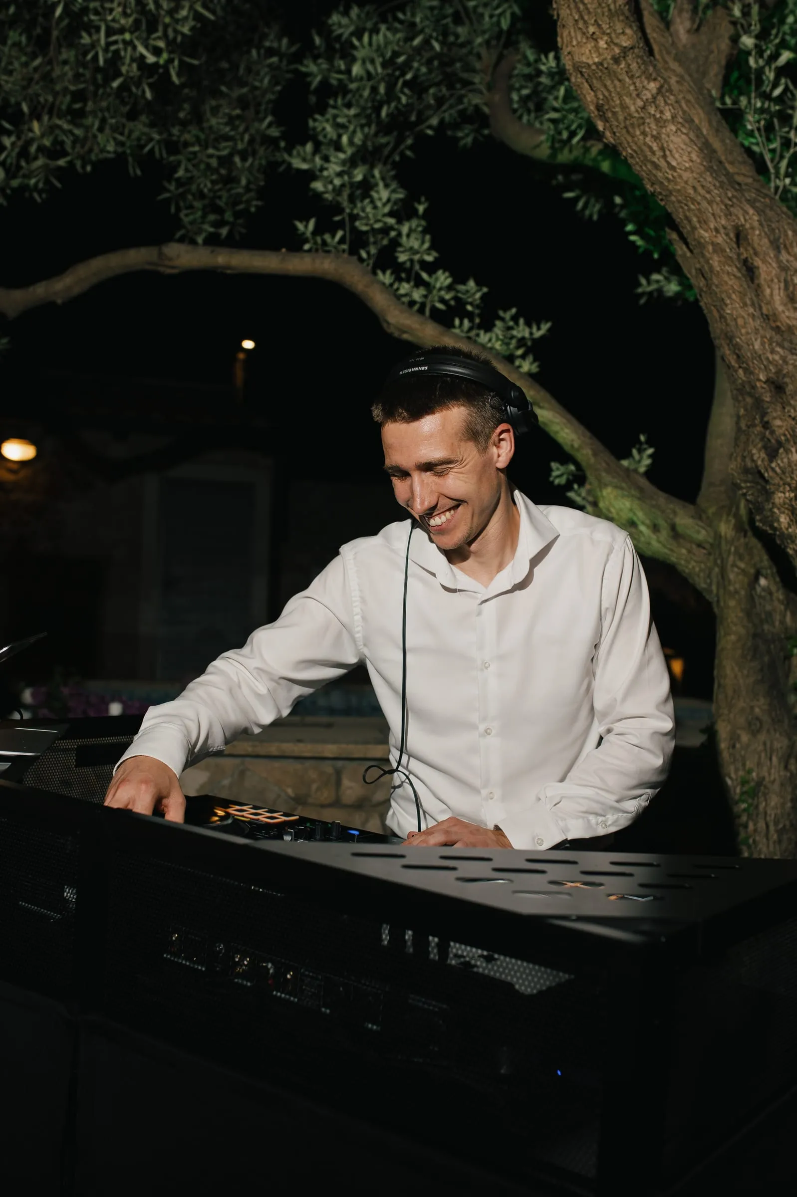 DJ Symart smiling at the decks under an olive tree at Villa Tereza near Dubrovnik